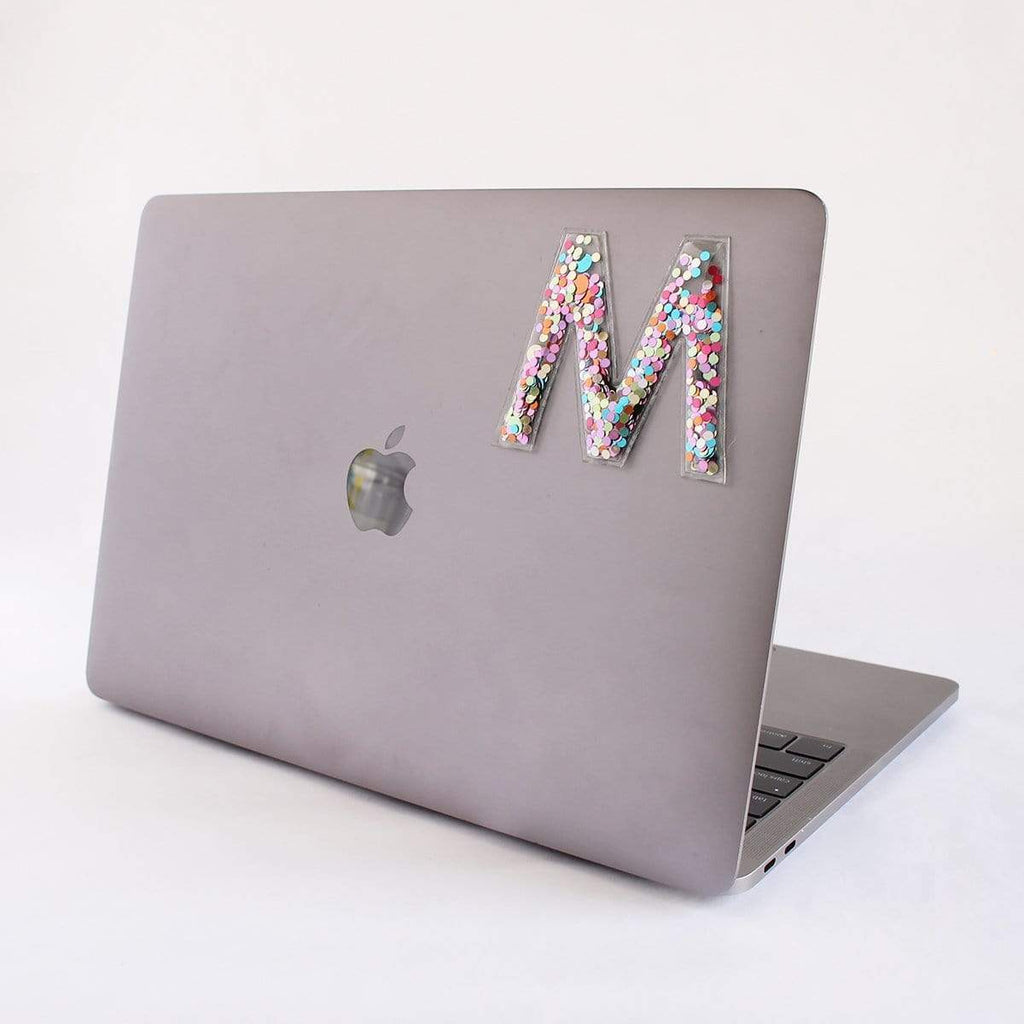 MacBook mit Konfetti Sticker Buchstabe M – transparenter Aufkleber mit buntem Konfetti, ideal für Technik und Alltagsgegenstände.